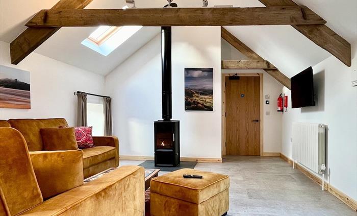 The large open plan lounge area has vaulted ceilings and a modern wood burning stove.